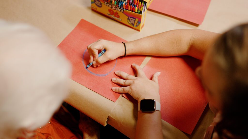 A woman is assisted by a nurse in a memory care therapy session
